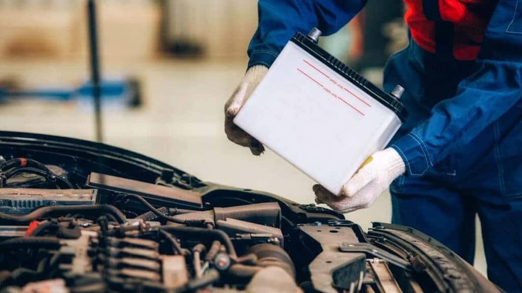 A technician installing a car battery as part of routine battery maintenance