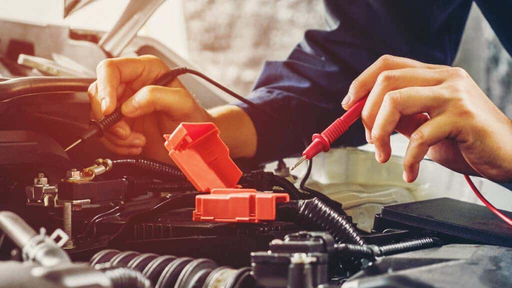 A technician testing a vehicle battery