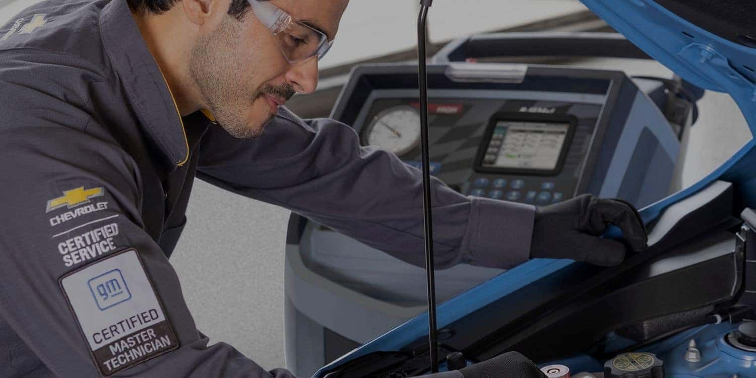 GM certified technician checking a vehicle under the hood with a diagnostic machine