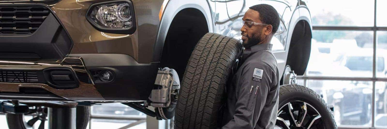Chevrolet service technician mounting a tire on a vehicle lift