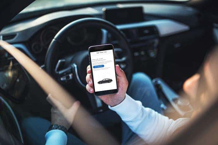 Person shopping for vehicles on their phone while sitting in their car