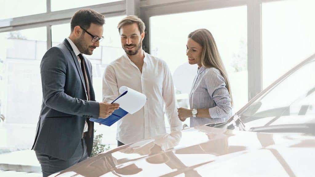 Couple talking to salesman next to vehicle-1221x686_x1221