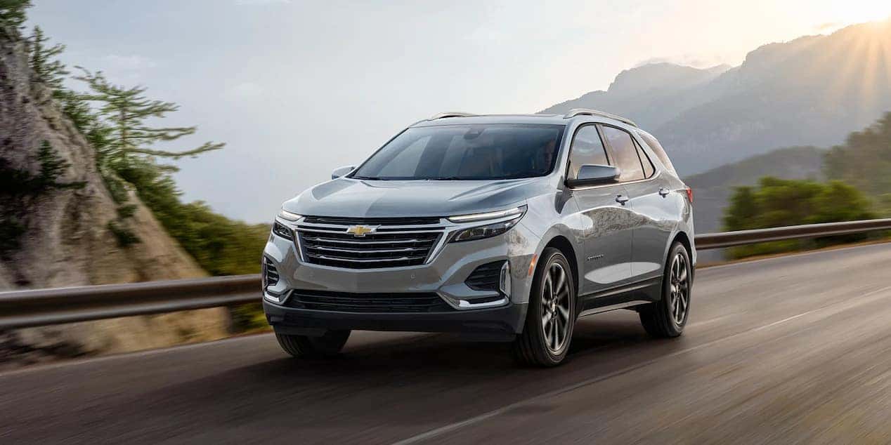 Grey 2023 Chevy Equinox driving quickly on a road surrounding the mountains