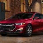 Red 2023 Chevrolet Malibu parked outside of a brick building in the city