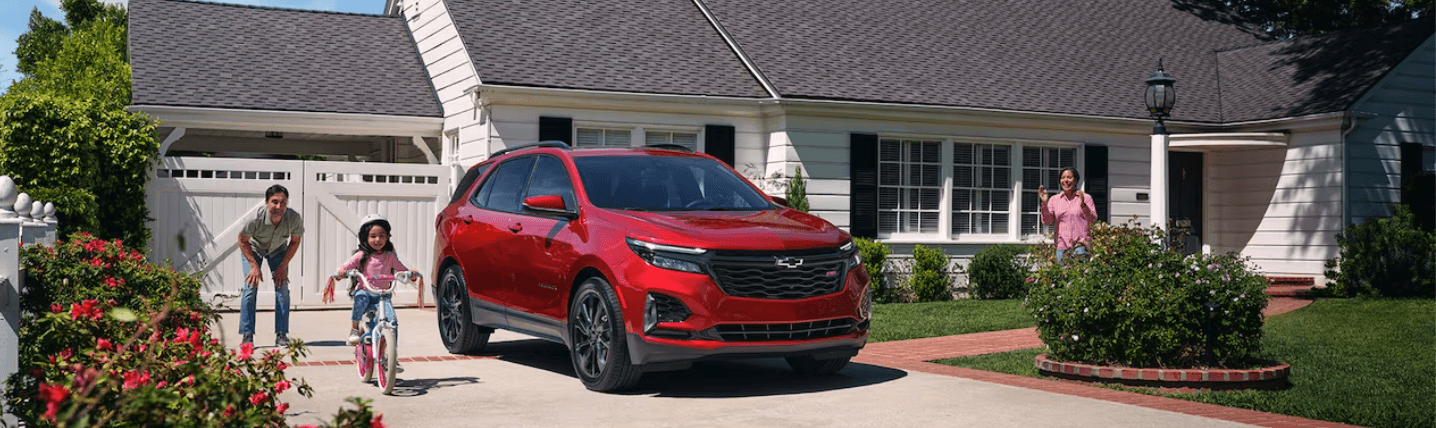 2024 Chevy Equinox parked in front of a home, next to a child on a bike