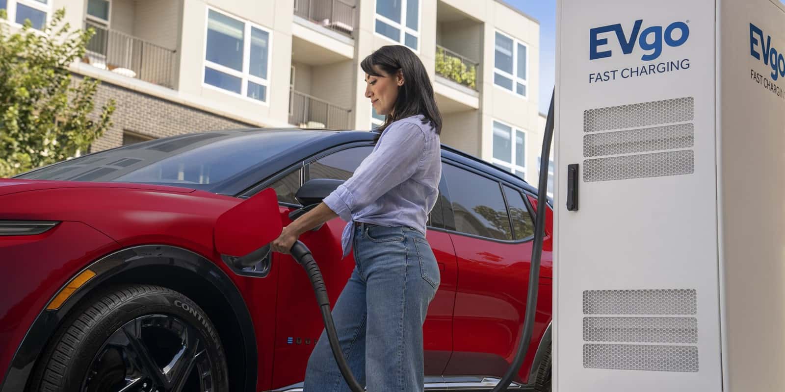 Driver plugging a Chevrolet EV into a public DC fast charging station — the type of stop used along the I-70 Mountain Corridor