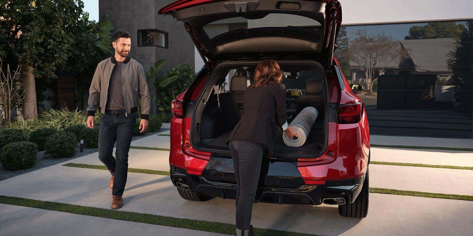Couple loading the cargo area of a red Chevy Blazer