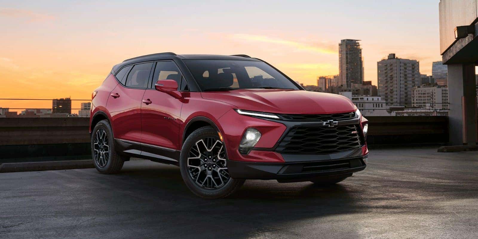 Red Chevy Blazer on a city rooftop at sunset
