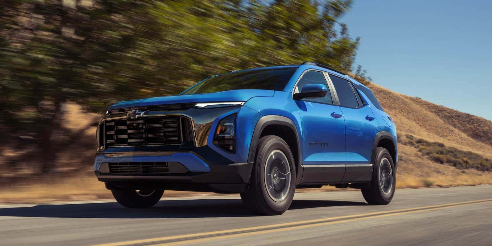 Blue Chevy Equinox driving on a two-lane road through dry hills