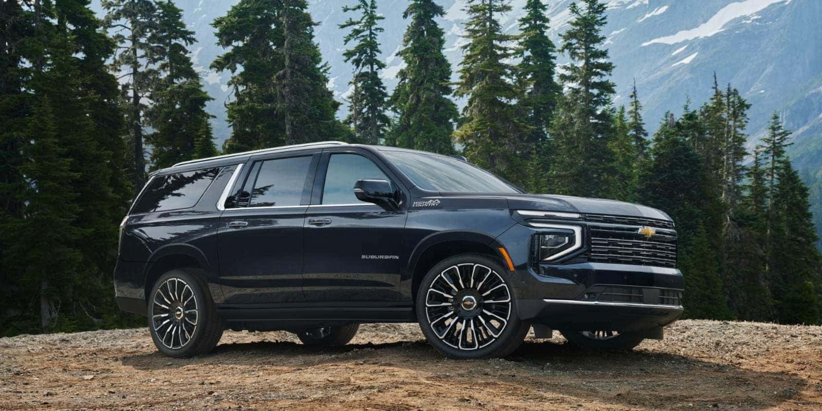 Black Chevy Suburban parked on a mountain trail among pine trees