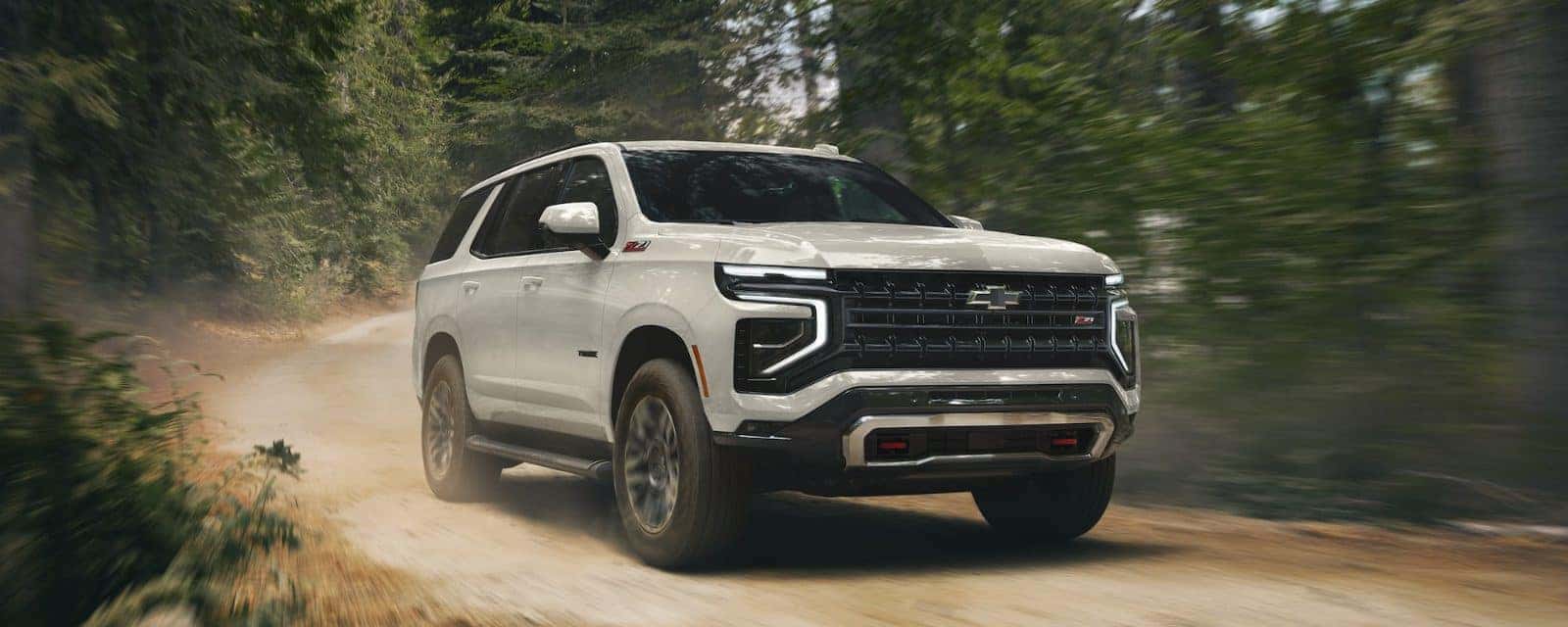 Chevy Tahoe driving on a dirt road through the forest
