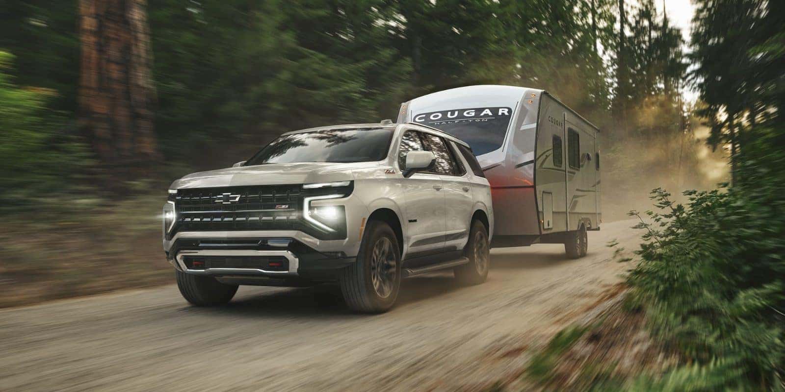 Chevy Tahoe towing a travel trailer on a forest road