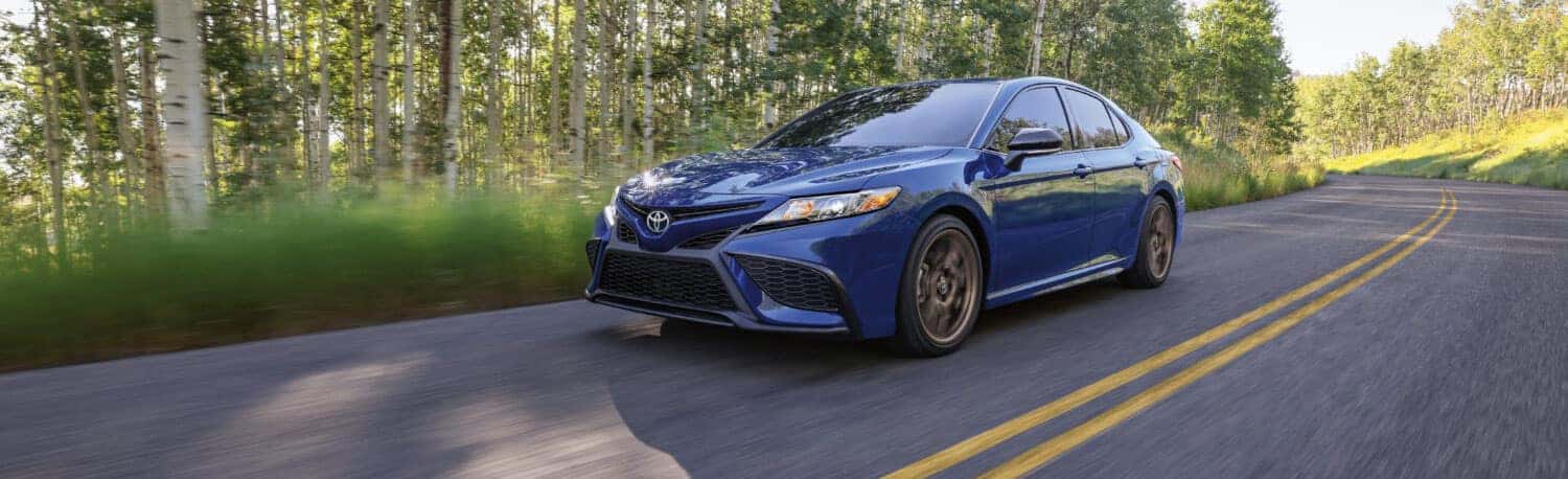 2024 Toyota Camry SE Nightshade driving on road in forest