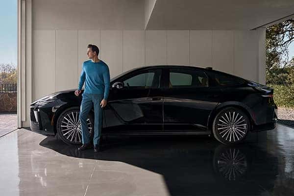 Lexus owner resting on their vehicle's open driver door while parked on the side of a street
