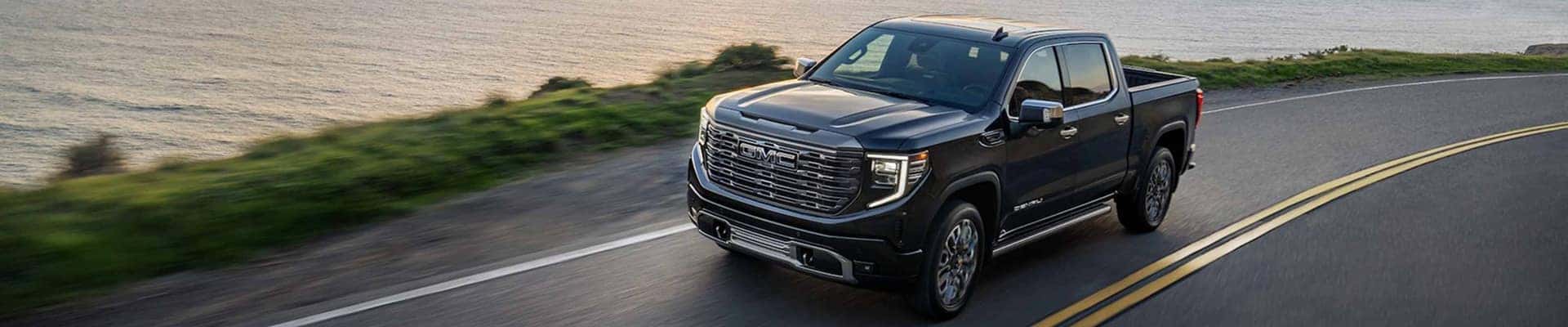 2026 gmc denali driving on road with water in background