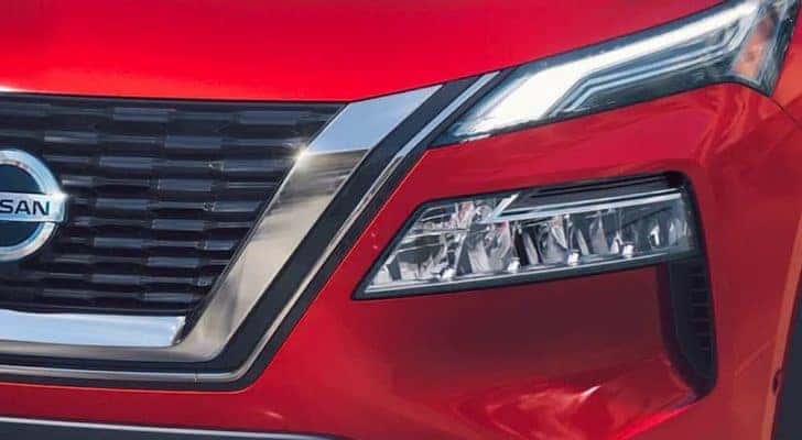 A closeup shows the grille of a red 2021 Nissan Rogue.
