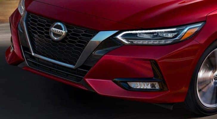 A closeup shows the grille of a red 2021 Nissan Sentra that is driving after leaving a car dealership in Nashville.
