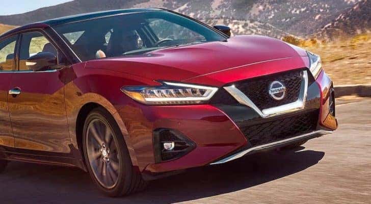 A red 2021 Nissan Maxima is driving on a highway after leaving a Hartsville Nissan dealer.