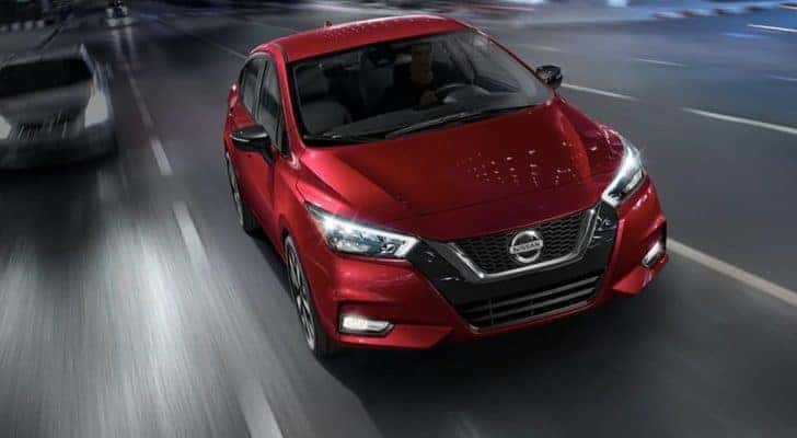 A red 2021 Nissan Versa is driving to a car dealer near you.