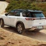 A white 2022 Nissan Pathfinder is shown off-roading on a dirt path.