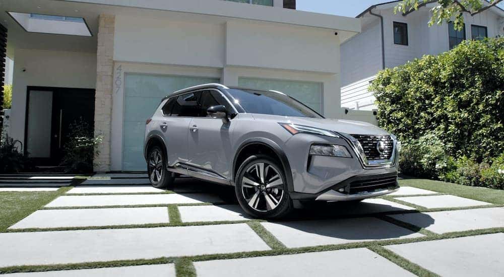 A silver 2022 Nissan Rogue is shown parked outside of a modern home after leaving a Nashville Nissan Rogue dealer.
