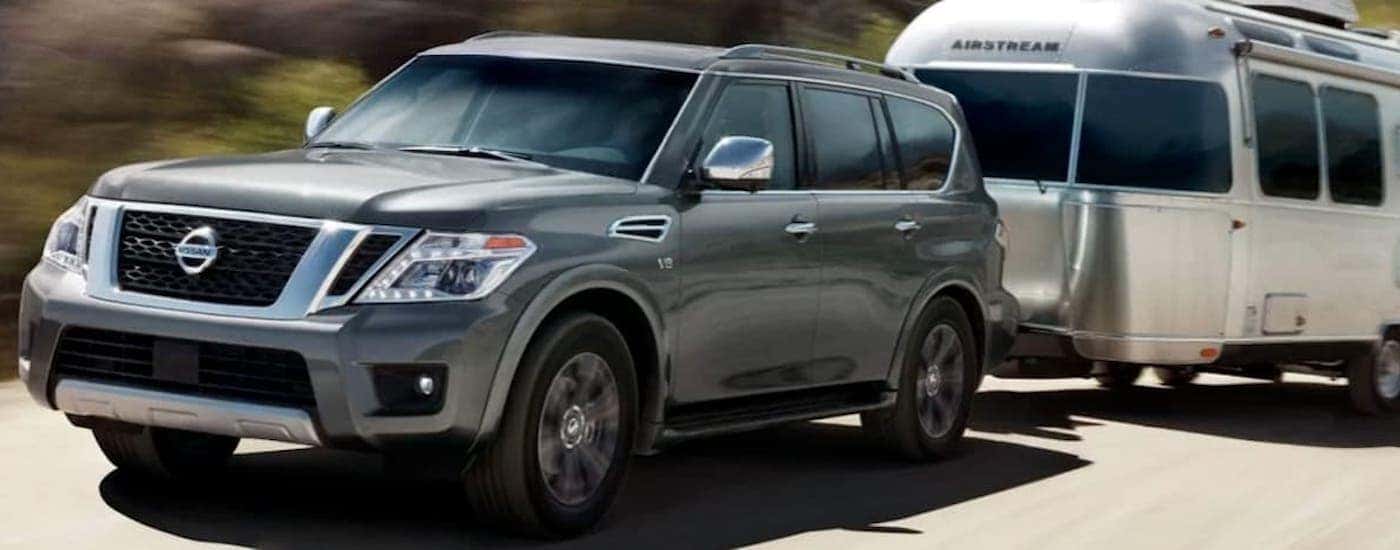 A grey 2019 Nissan Armada is shown towing a camper on an open road.
