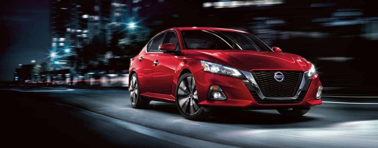 A red 2022 Nissan Altima is shown from the front driving on an open road.