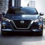 A blue 2020 Nissan Altima is shown from the front driving through a city after leaving a Certified pre-owned Nissan dealer in Nashville.
