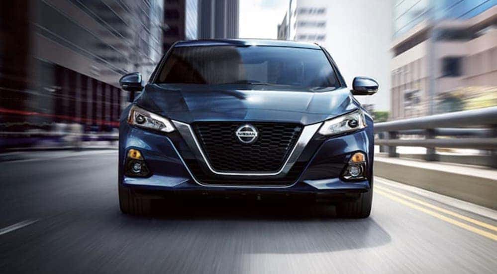 A blue 2020 Nissan Altima is shown from the front driving through a city after leaving a Certified pre-owned Nissan dealer in Nashville.