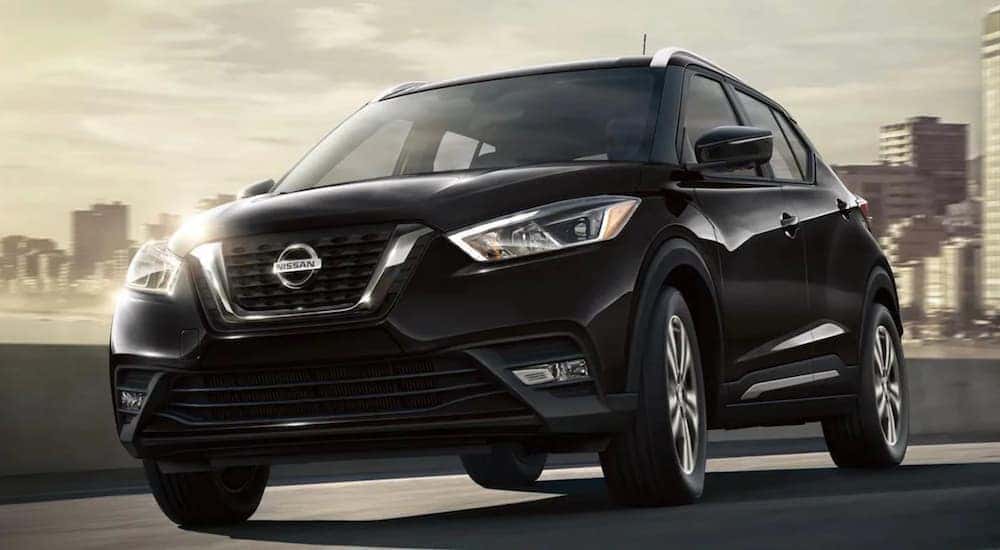 A black 2020 Nissan Kicks is shown from the front driving on an open road.