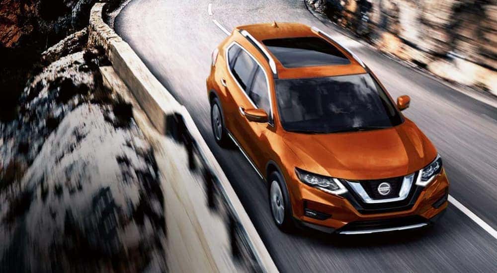 An orange 2020 Nissan Rogue is shown from above driving on an open road.