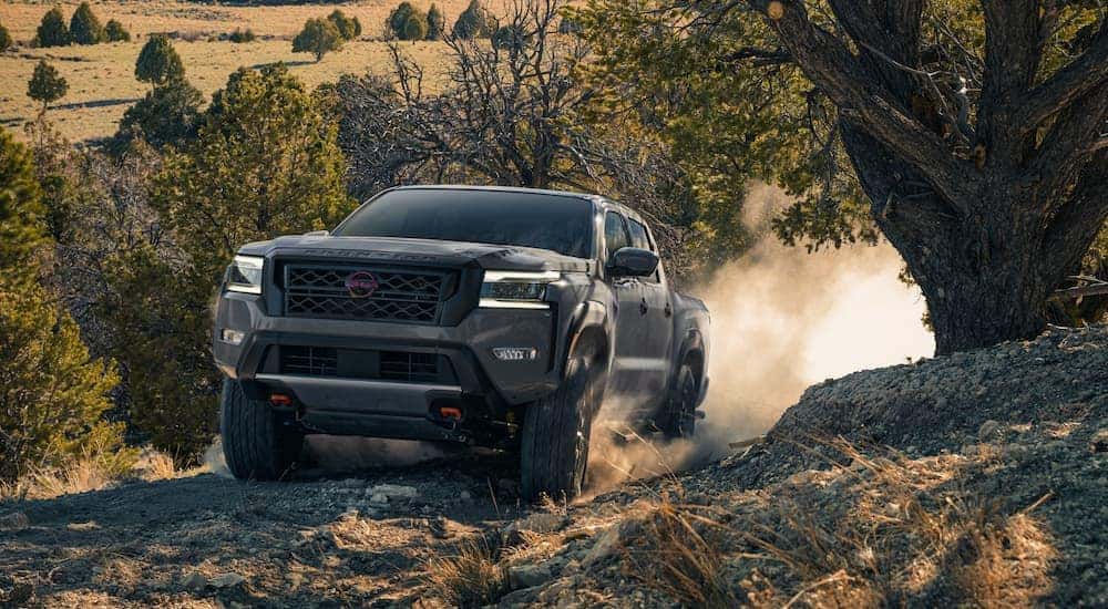 A grey 2022 Nissan Frontier PRO-4X is shown driving up a steep hill.