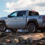 A popular lifted truck, a silver 2022 Nissan Frontier PRO-4X is shown parked on top of a rocky mountain trail.