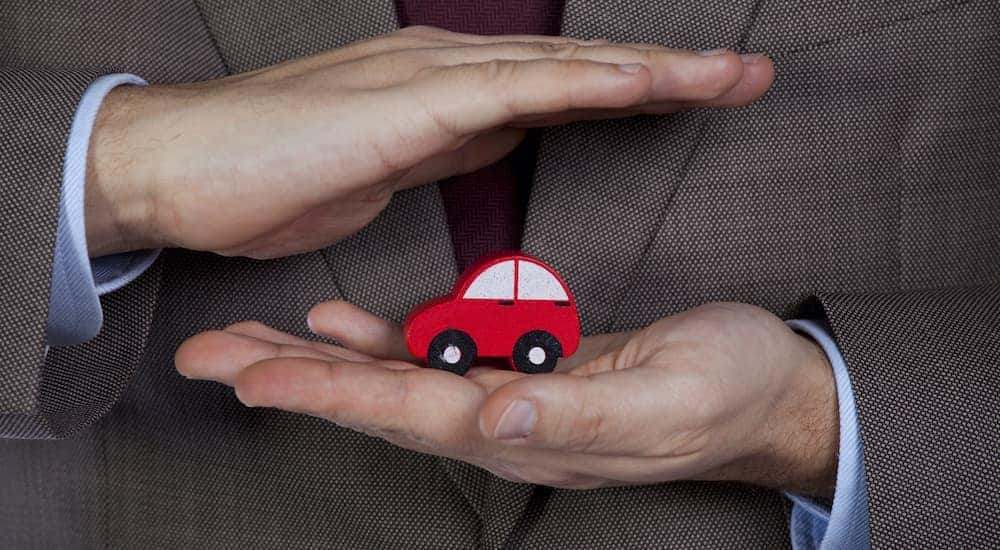 A salesperson is shown holding a wooden block in the shape of a car.