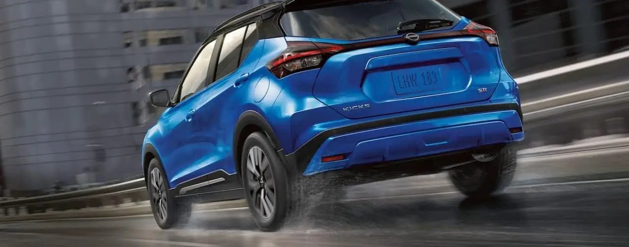 A blue 2022 Nissan Kicks SR is shown from the rear driving on an open highway.