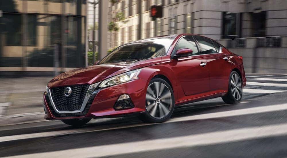 A red 2022 Nissan Altima is shown rounding a corner in a city after leaving Goodlettsville Nissan dealer.
