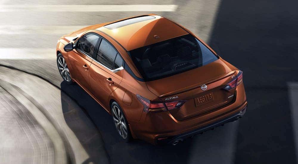An orange 2022 Nissan Altima is shown rounding a corner from above.