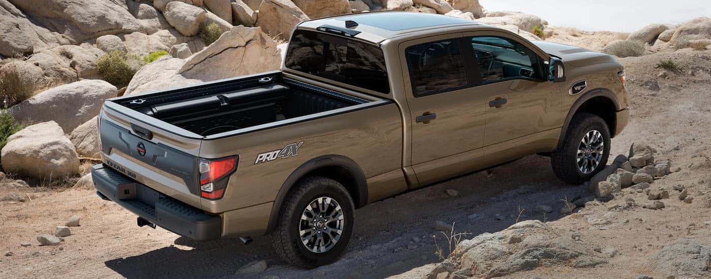 A tan 2022 Nissan Titan is shown from the side off-roading in a desert.