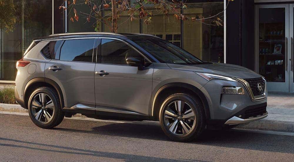 A grey 2022 Nissan Rogue is shown from the side parked in front of a house.