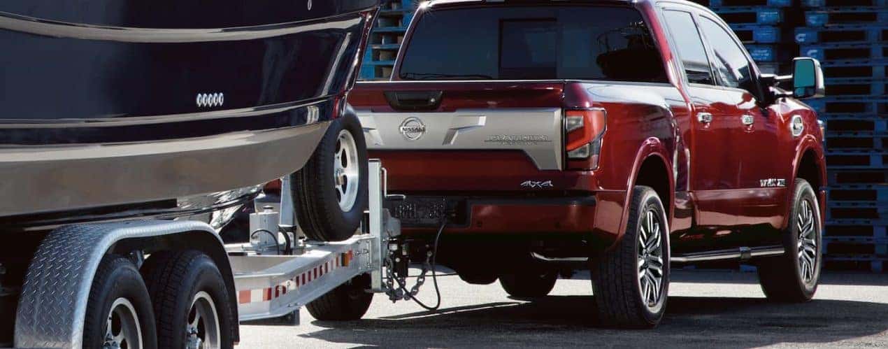 A red 2022 Nissan Titan Platinum is shown towing a boat.