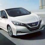 A white 2022 Nissan LEAF driving on an open road.