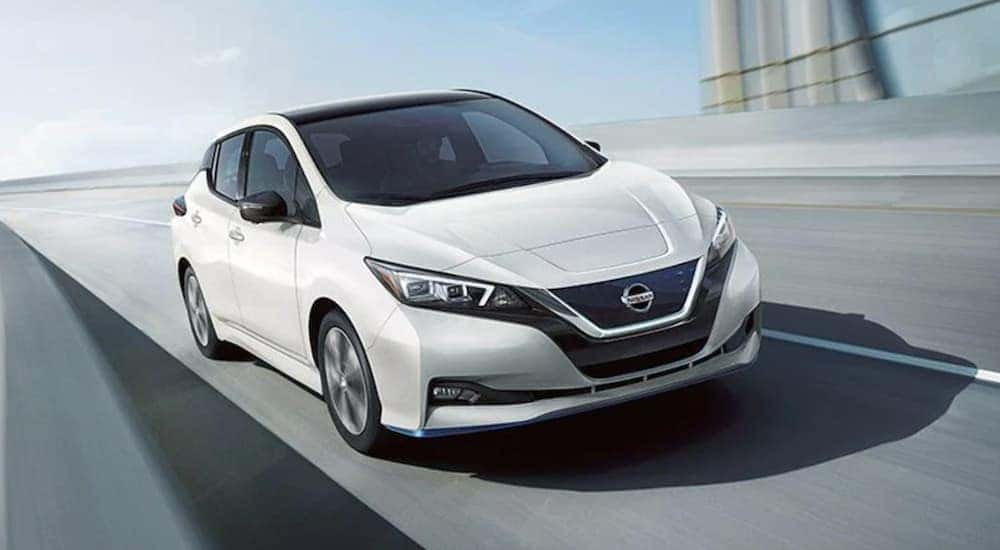 A white 2022 Nissan LEAF driving on an open road.