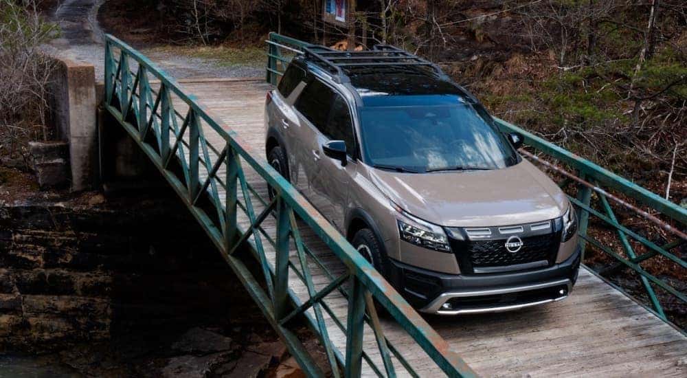 Aerial view of a brown 2023 Nissan Pathfinder Rock Creek driving across a small wooden bridge