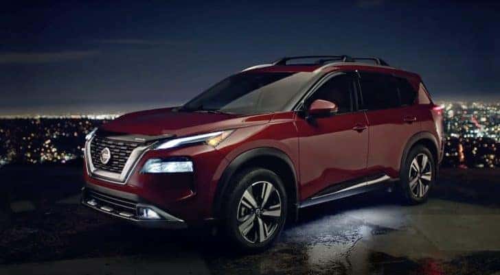 A red 2021 Nissan Rogue is shown from the side parked at night.