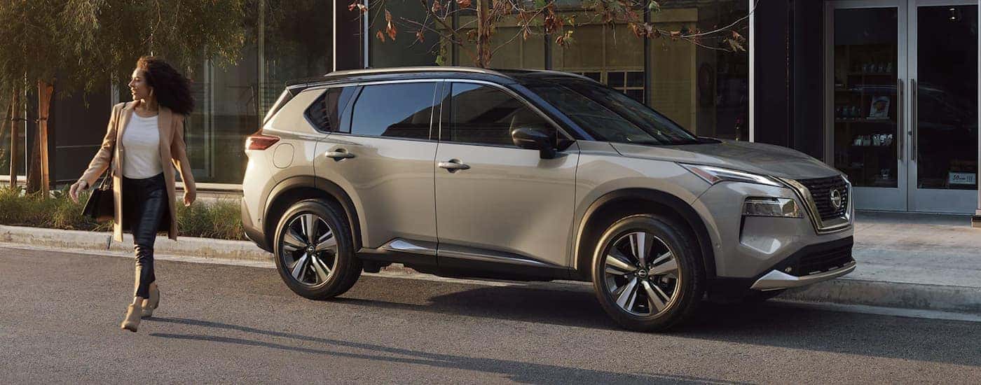 A grey 2022 Nissan Rogue is shown from the side parked in front of a store.