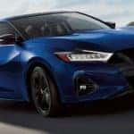 Front view of a blue 2021 Nissan Maxima driving past mountains