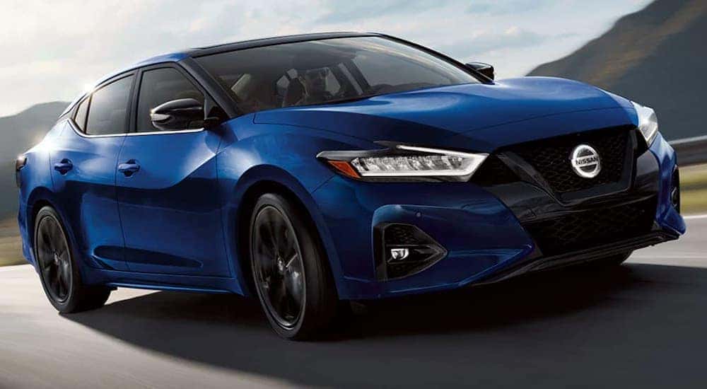 Front view of a blue 2021 Nissan Maxima driving past mountains