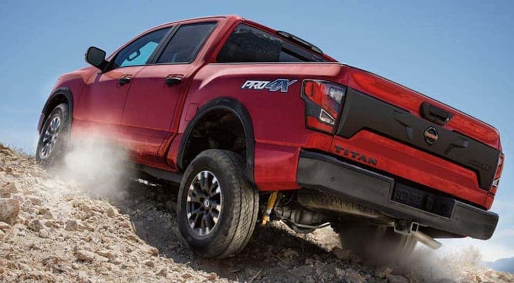 Seen from below, a red 2021 Nissan Titan Pro4x off-roads up a mountain of rocks
