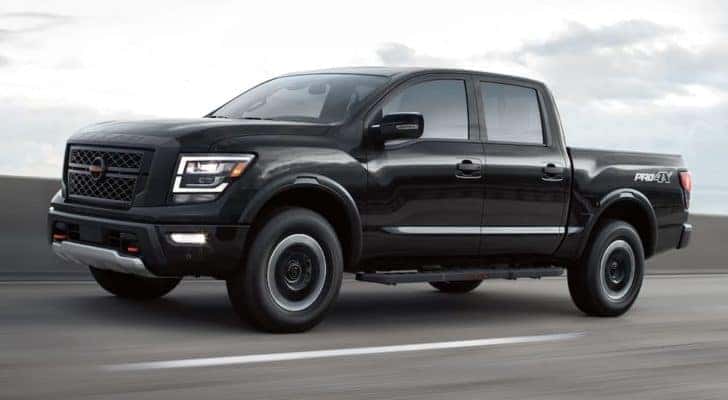 A black 2022 Nissan Titan Pro4x is shown from the side driving on an open road.