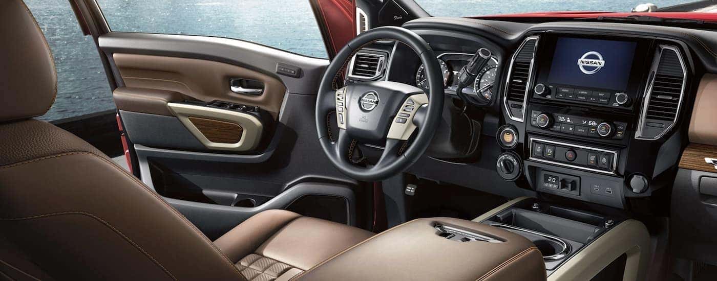 The black and tan interior of a 2022 Nissan Titan shows the steering wheel and infotainment screen.